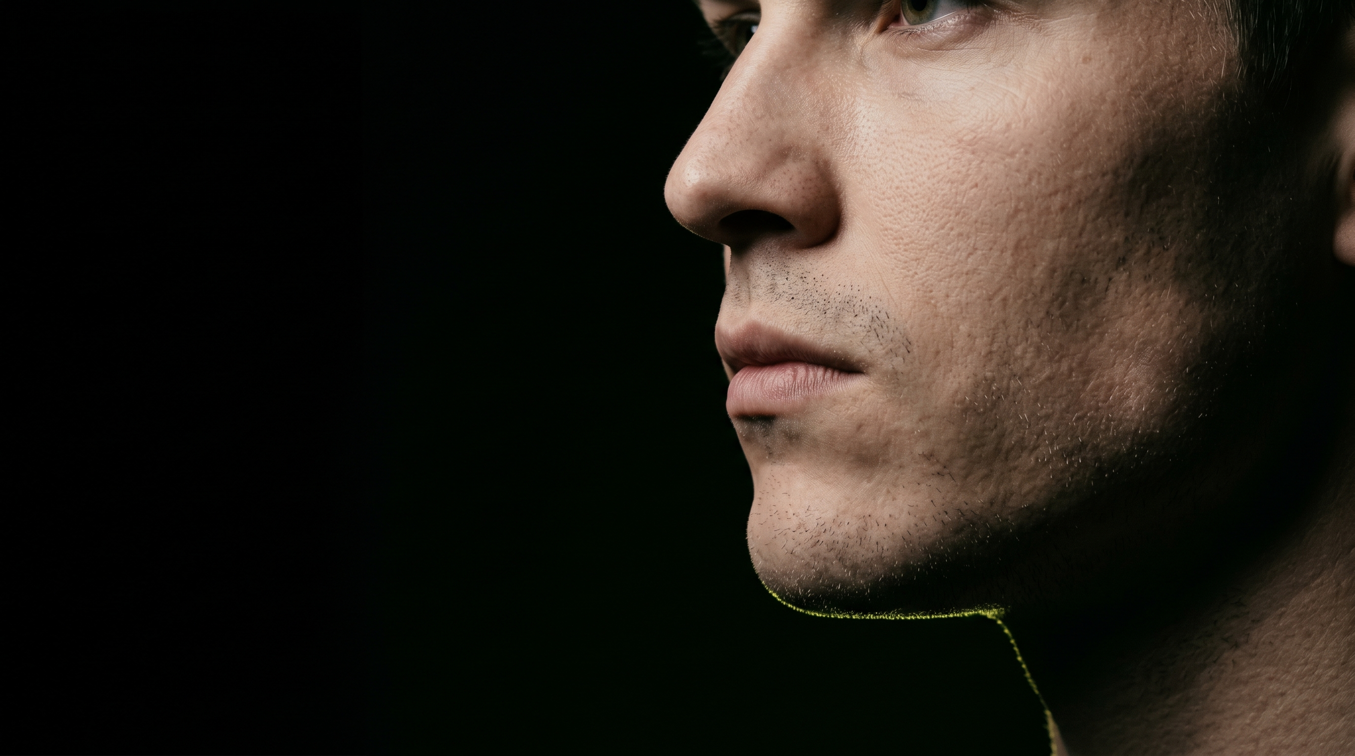 Editorial close-up profile of a young man's jawline with cold rim lighting tracing the mandible in acid lime